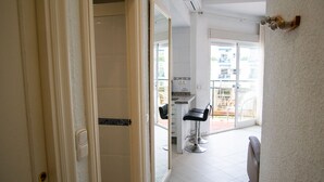 Un couloir d’hôtel donnant accès à une salle de bain, un salon et offrant une vue sur l’extérieur.