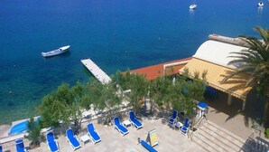 A pool area with lounge chairs and a view of the sea. - Comfortable Croatian Couple Retreat (Novalja)