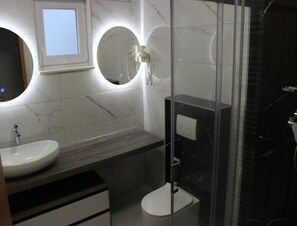 A modern bathroom with a marble vanity, a round mirror, and a glass shower enclosure. - Comfortable Croatian Couple Retreat (Novalja)