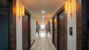 Ein moderner Hotelkorridor mit Holzvertäfelung, Marmorboden und Wandleuchten.