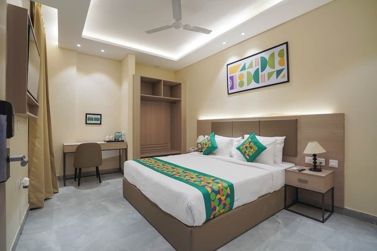 A hotel room with a bed, desk, chair, wardrobe, and a ceiling fan.