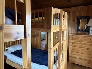 A wooden bunk bed with a dresser and a mirror. - Experience ocean views in the spacious 6-bedroom Boathouse in Ferry Beach, Saco, ME. (Saco)