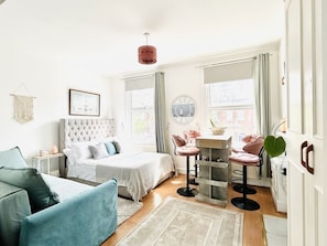 A modern bedroom with a bed, a sitting area with a table and chairs, and a large window with curtains. - The Hammersmith River studio- central, cosy and well designed (London)
