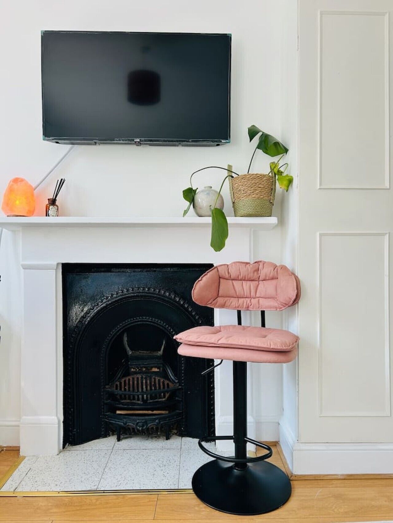 Ein modernes Wohnzimmer mit Kamin, einem an der Wand montierten Fernseher und einem rosa Sessel.