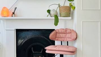 Ein modernes Wohnzimmer mit Kamin, einem an der Wand montierten Fernseher und einem rosa Sessel.