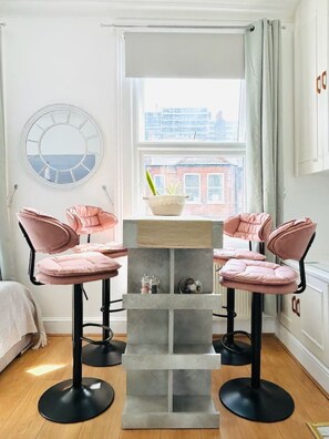 Een modern interieur met een ronde spiegel, een raam met uitzicht op gebouwen, en een tafel met stoelen.