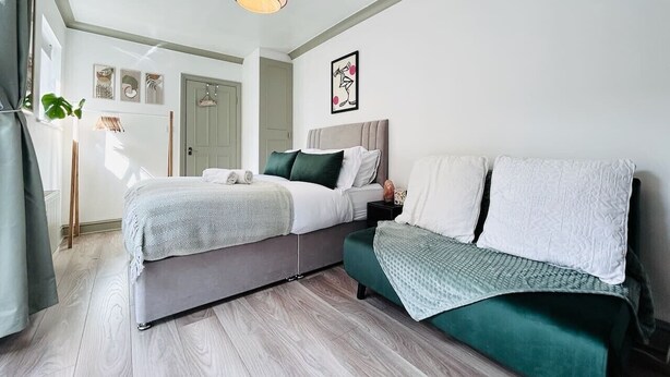 Un dormitorio moderno con cama, mesitas de noche y un sofá verde.