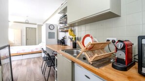 Una cocina compacta con encimera de madera, lavavajillas integrado y una cafetera roja.