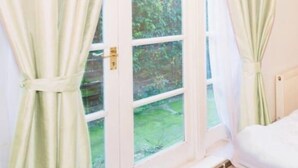 Una habitación con ventana, cortinas y cama.