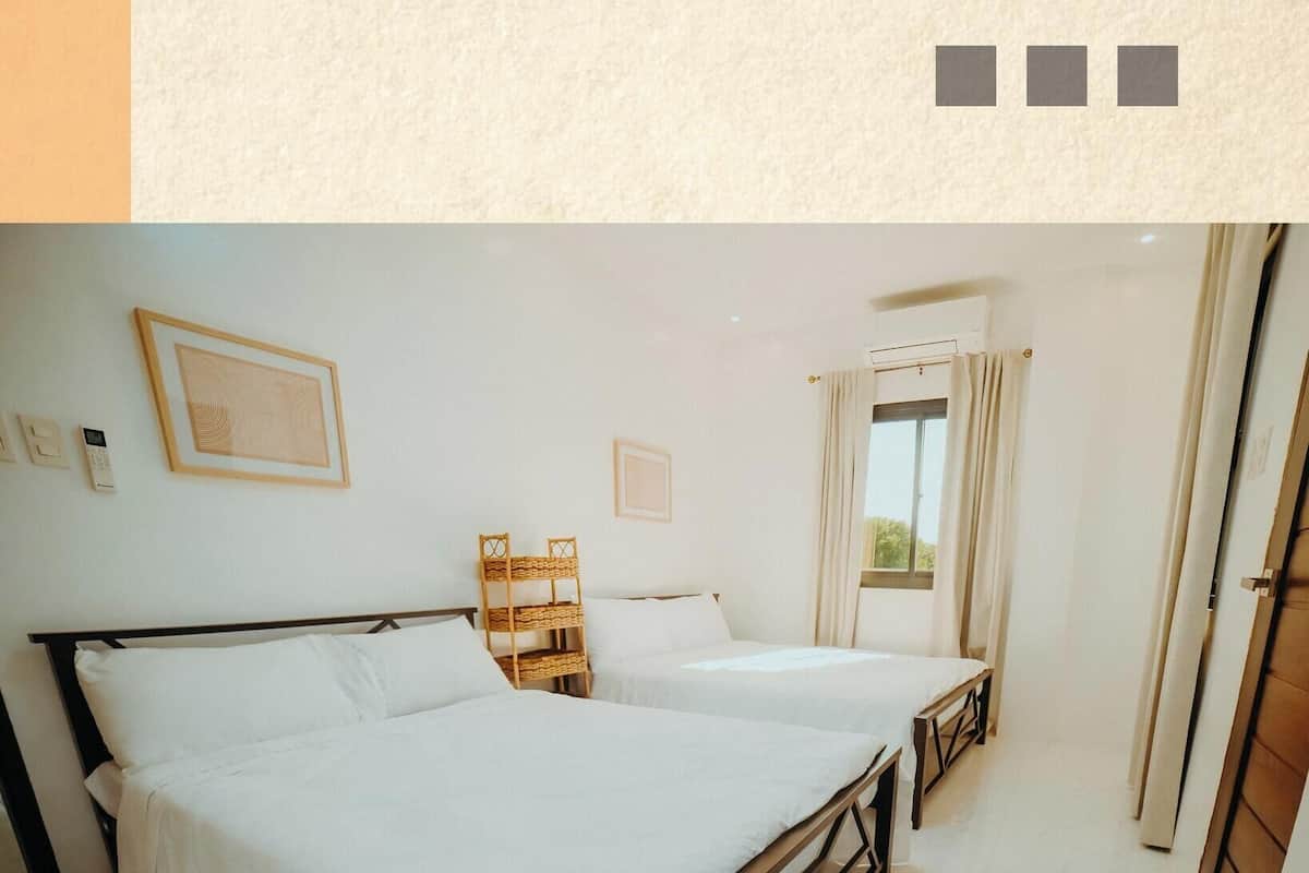 Habitación de hotel con dos camas, una silla de madera, una mesita y una ventana con cortinas.