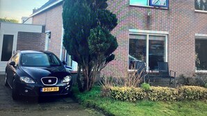 Ein Ziegelhaus mit einem Auto auf der Auffahrt, einem Baum davor und blauem Himmel.