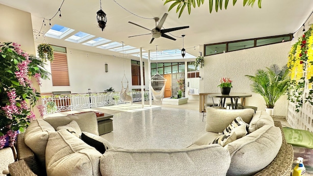 A spacious indoor area with a round seating arrangement, a ceiling fan, and hanging plants. - Spacious 6 & 8 bedroom Chalet Vista al Mar with AC and solar power in Aguadilla (aguadilla)