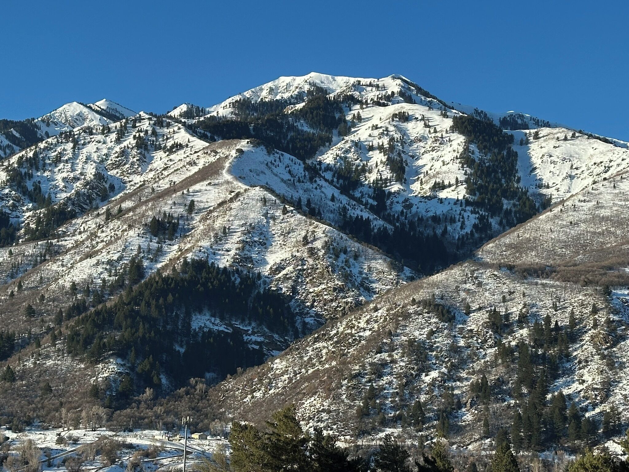 Un paysage de montagne avec des pentes enneigées et un ciel bleu dégagé.