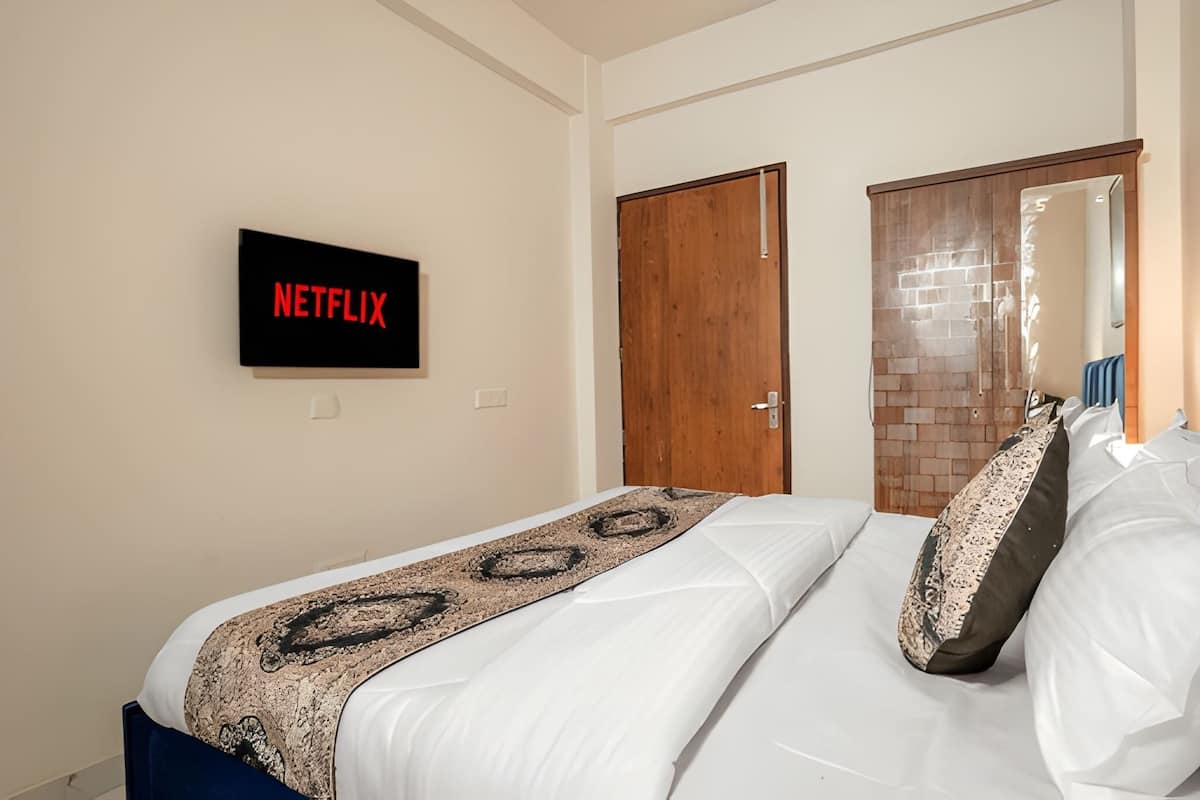 Hotellihuone, jossa on sänky, puuovi, seinälle kiinnitetty kyltti ja peili.