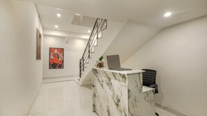 A reception desk with a laptop, a staircase, and a framed picture on the wall. - COZY COVE (Dera Bassi)