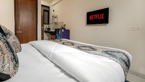 A bedroom with a bed, a wall-mounted Netflix sign, a door, and a desk with a computer. - COZY COVE (Dera Bassi)