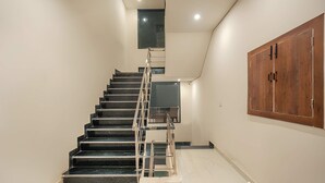A staircase with a metal handrail, a wooden wardrobe, and a small window at the top. - COZY COVE (Dera Bassi)