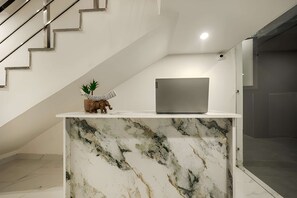 A marble counter with a laptop, a small elephant figurine, and a plant. - COZY COVE (Dera Bassi)