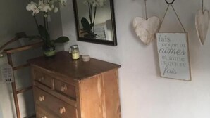 A room with a wooden dresser, a mirror, and a shelf with heart-shaped decorations. - Les Studios de la Côte Roz: Voyageur Solo, (Perros-Guirec)