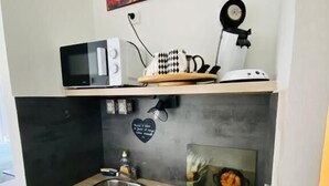 Una kitchenette compacta con microondas, tostadora y horno pequeño.