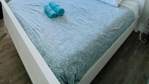 Un dormitorio con cama, ventana, espejo y un adorno en la pared.