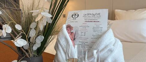Une chambre d’hôtel avec un lit, une table de chevet sur laquelle se trouve un verre d’eau, un menu et une plante décorative.