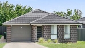A single-story house with a brick facade, a grey roof, and a garage door. - THE QUARTERS #1 Centrally located modern 2 bed unit featuring stylish decor (East Tamworth)