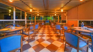 A restaurant with checkered flooring, wooden tables, and chairs. - Hotel Silver Leaf (Panchgani)