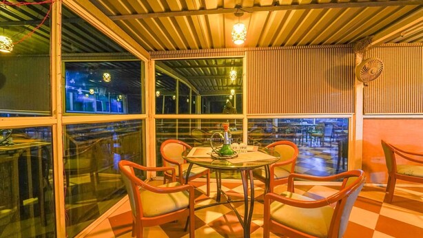 An indoor dining area with a checkered floor, round tables, and orange chairs. - Hotel Silver Leaf (Panchgani)