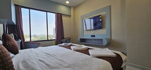 A hotel room with a large bed, a television mounted on the wall, and a view of the city through the window. - Hotel Velvet Vista (Sanand)