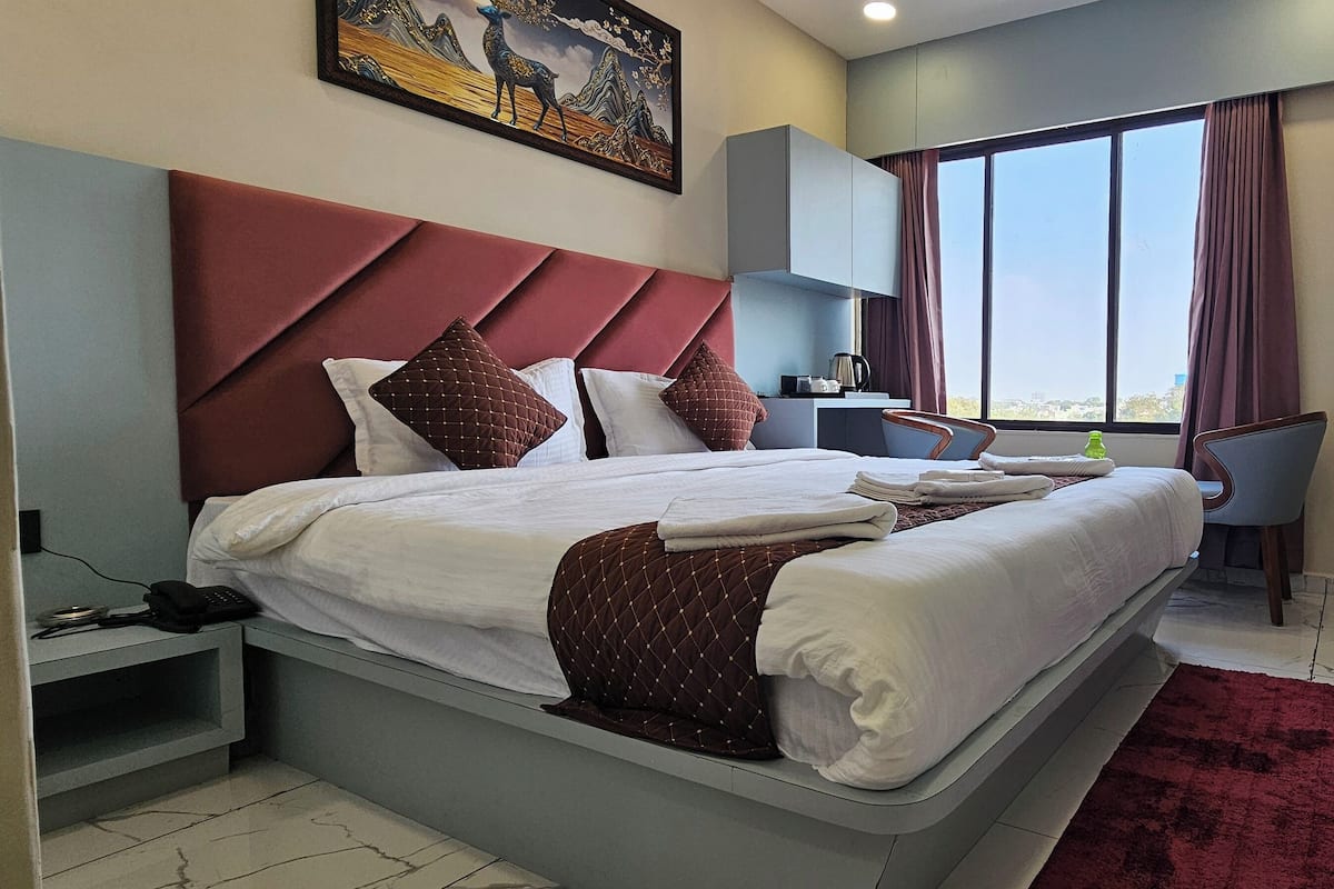 A modern hotel room with a large bed, a desk, and a TV.