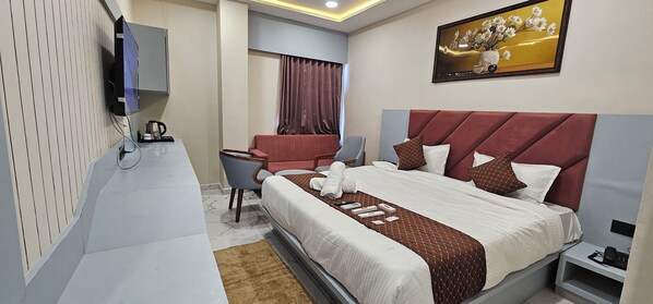 Une chambre d’hôtel avec un grand lit, un bureau, une chaise et un téléviseur.