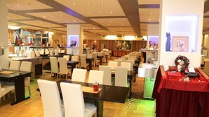 A hotel dining area with multiple tables and chairs, a reception desk, and Christmas decorations. - Carea Harz Hotel Allrode (Thale)