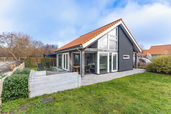 Une maison moderne avec un toit en pente, de grandes fenêtres et une terrasse.