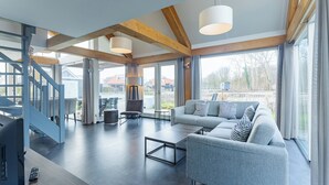 Un vaste espace de vie comprenant un canapé moderne, une table basse et un escalier menant à un niveau supérieur.