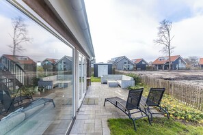 Une terrasse extérieure moderne, aménagée avec des sièges et offrant une vue sur les maisons voisines.