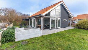 Une maison moderne avec un toit en pente, de grandes fenêtres et un espace patio.