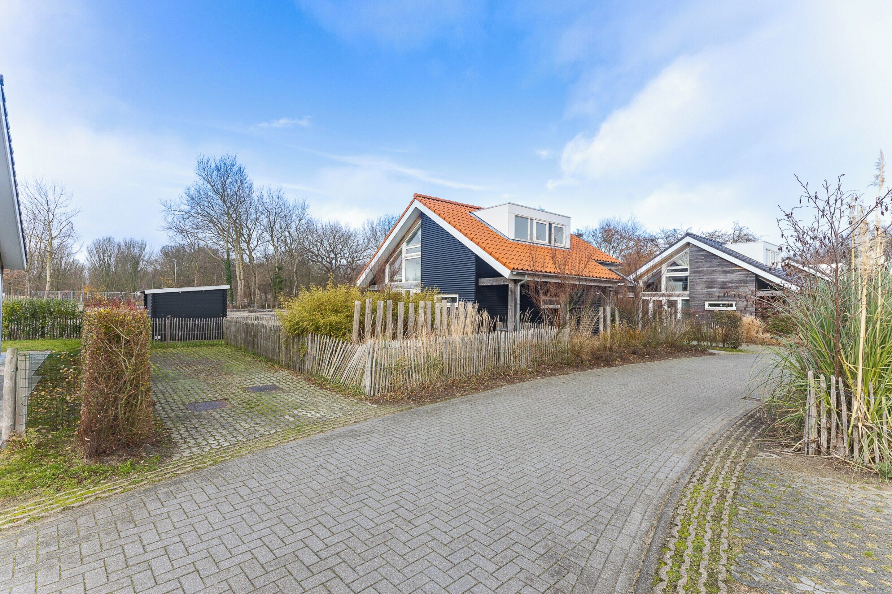 Een woonwijk met een verharde oprit die leidt naar huizen met rode pannendaken en houten omheiningen.