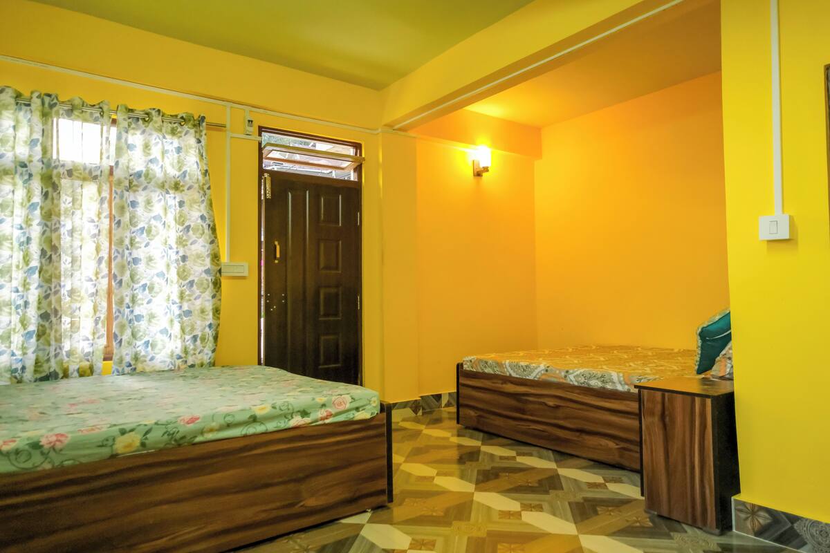 A bedroom with two wooden beds, a checkered floor, and a yellow wall.
