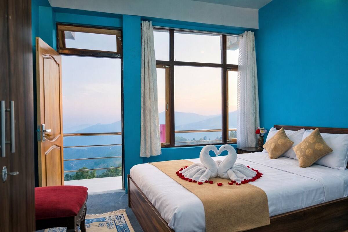 A bedroom with a bed, a bench, and a view of mountains through large windows.
