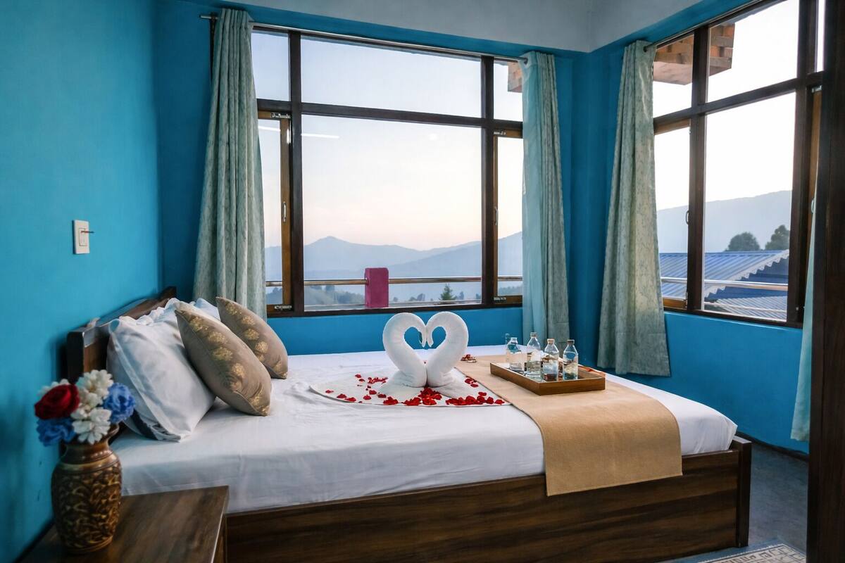 A bedroom with a bed, a heart-shaped towel, and a tray of water bottles.