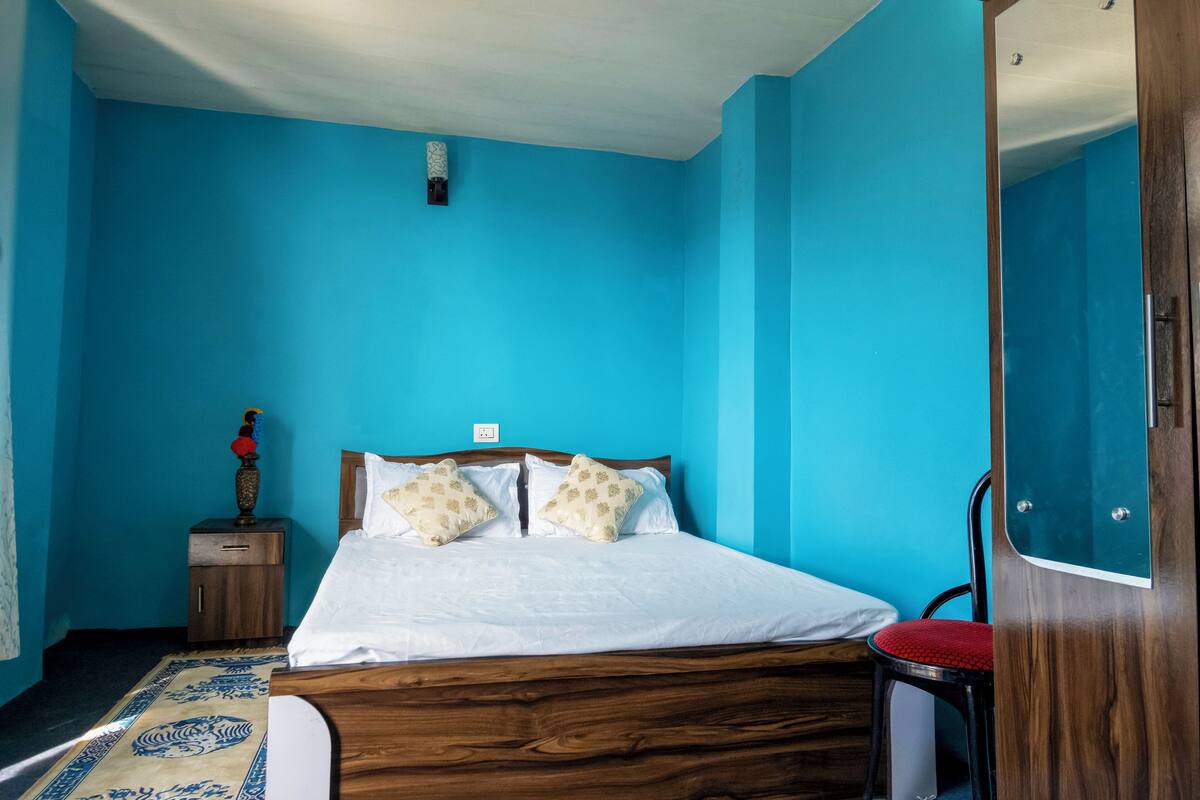 A room with a wooden bed, a nightstand, a red chair, and a blue wall.
