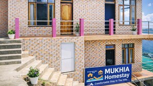 A two-story building with a stone facade, balconies with metal railings, and a sign for MUKHIA Homestay. - Mukhia Homestay (Kurseong)