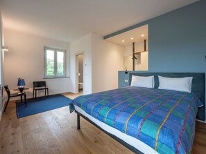 Ein Schlafzimmer mit einem großen Bett, einem Schreibtisch, einem Stuhl und einem Fenster.