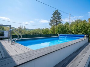 A swimming pool with a metal ladder, surrounded by a wooden deck and a green fence. - Stunning private villa with private pool, WIFI, A/C, terrace, pets allowed and panoramic view (Piano-molini D'isola)
