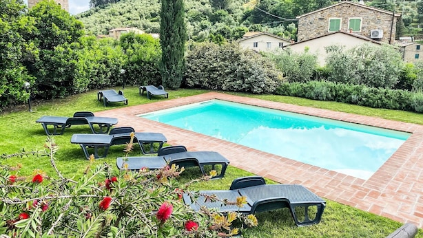 A swimming pool with lounge chairs, surrounded by well-maintained grass and hedges, with a stone building and a tower in the background. - Beautiful private villa for 10 guests with private pool, WIFI, TV, balcony and pets allowed (Capannori)