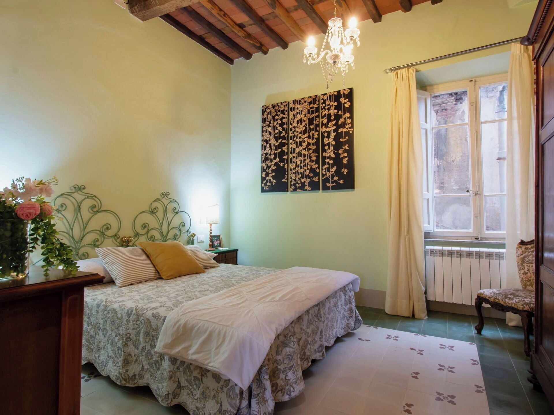 Ein Schlafzimmer mit Bett, einer Deckenleuchte, einem Fenster mit Vorhängen und einer Heizung.