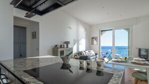 Et moderne køkken med en stor marmorbordplade, indbygget komfur og spiseområde med havudsigt.