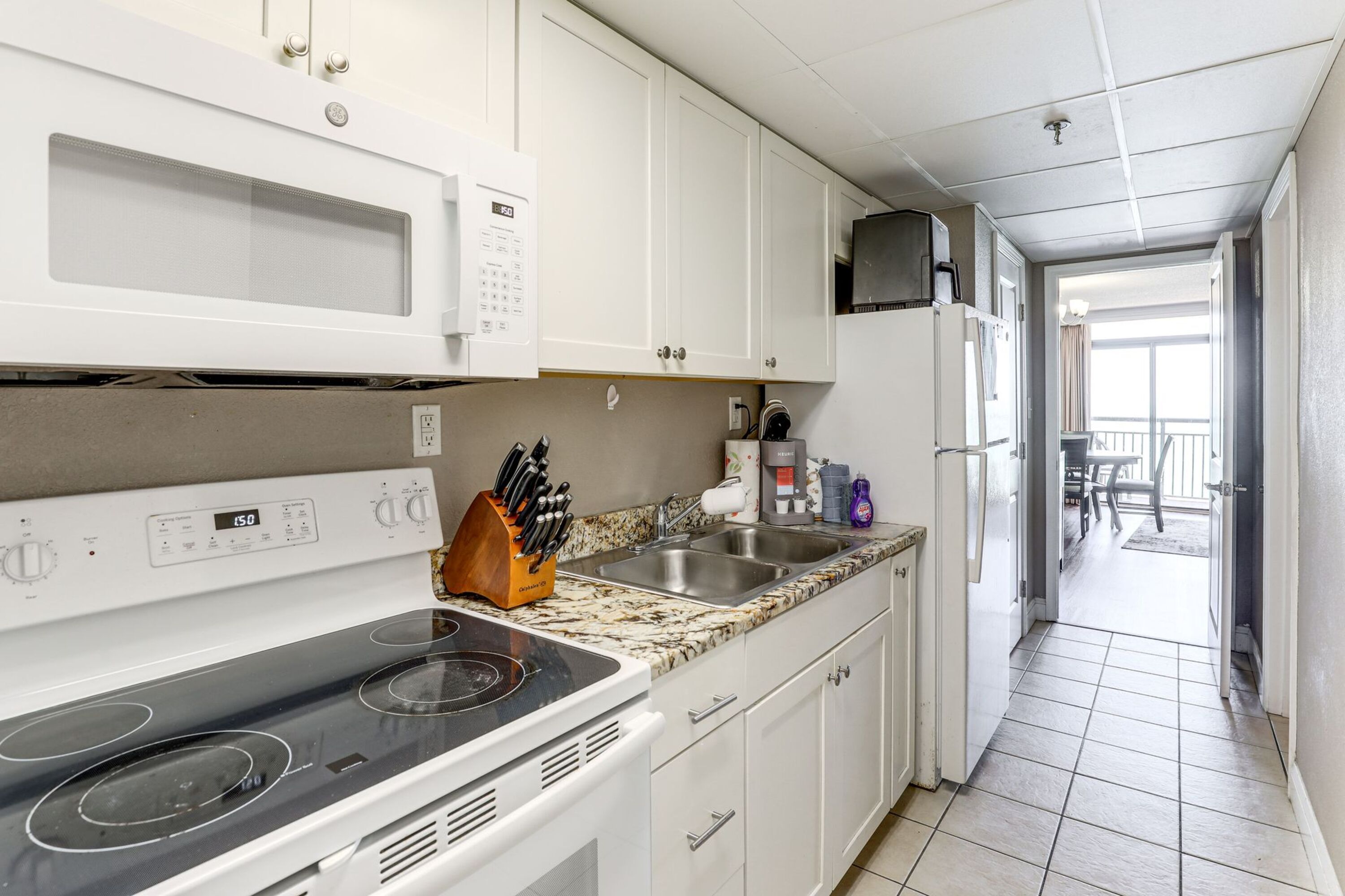 A kitchen with white cabinets, a microwave, a stove, and a sink.