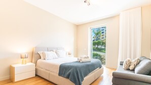 A modern bedroom with a bed, bedside tables, a sofa, and a view of the outdoors. - Pearl View by Atlantic Holiday (Funchal)